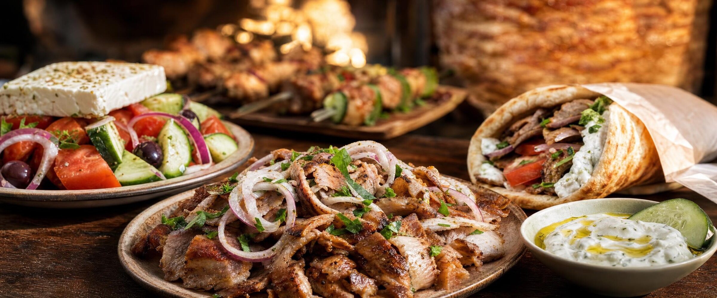 Griechische Gerichte: Gyros vom Drehspiess mit Zwiebeln, Bauernsalat mit Feta, gefuellte Pita und Tzatziki. Mit KI erzeugtes Symbolbild.